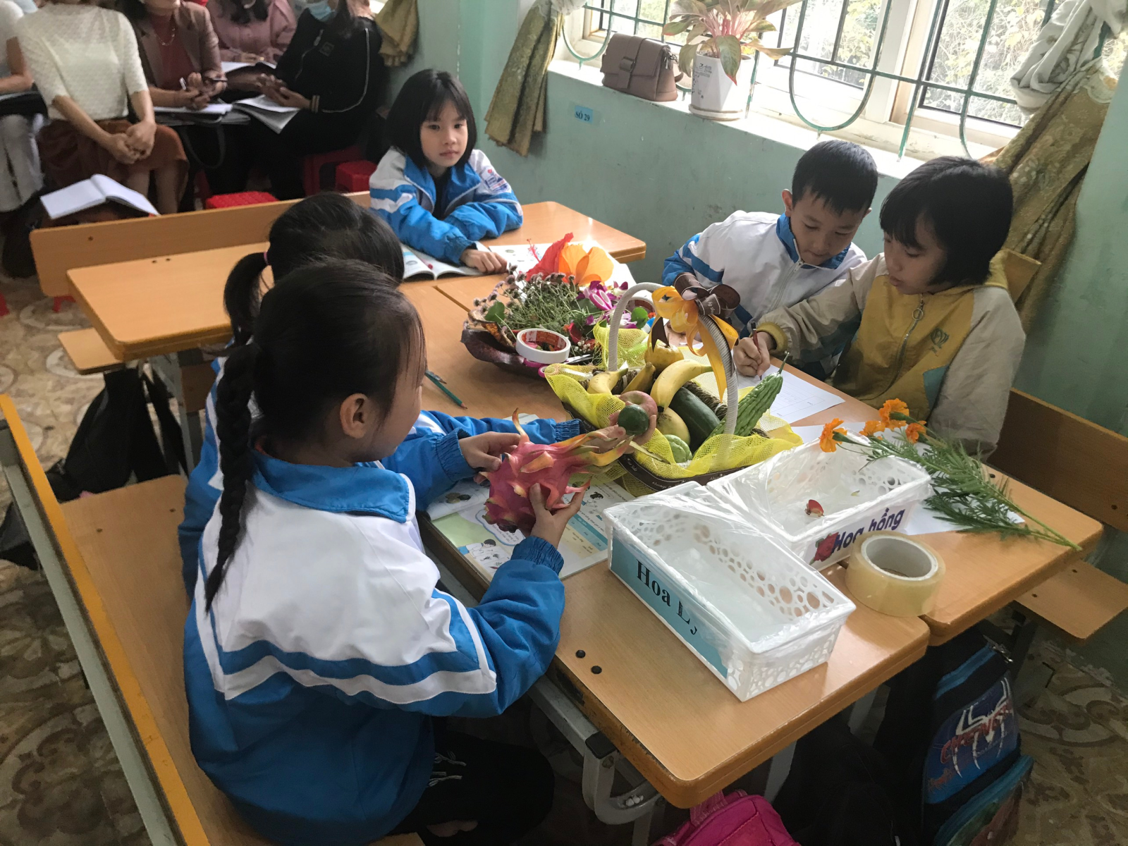 A group of children sitting at a table with flowers Description automatically generated with low confidence